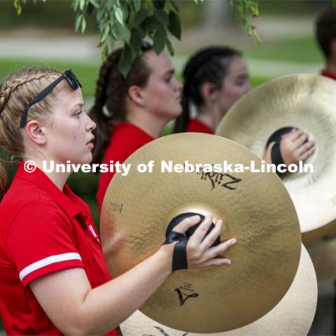 Kelly Fedderson and the rest of the cymbal line performs before the Cornhusker Marching Band Exhibition. Big Red Welcome week featured the Cornhusker Marching Band Exhibition. The band gave their warm-up concert outside of Kimball Recital Hall and then marched to the stadium. Lightning then caused the show to be cancelled. August 20, 2021. Photo by Craig Chandler / University Communication.