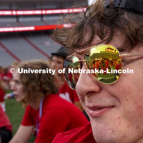 Grady Wright, a first-year student from Minden, NE, listens as ASUN President Batool Ibrahim on the video board is reflected in his sunglasses. Tunnel Walk for freshman (class of 2025) and incoming new students. First year students tunnel walk. August 20, 2021. Photo by Craig Chandler/ University Communication.