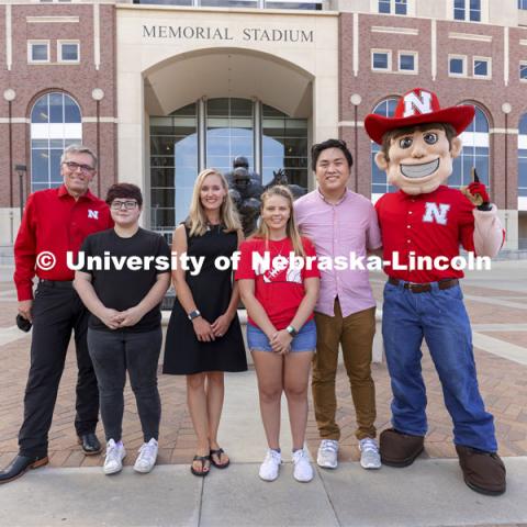Chancellor Ronnie Green and Herbie stand outside Memorial Stadium on either side of the Voluntary COVID-19 Vaccine Registry grand prize winners (from left) Alex Chytil, Jenna Huttenmaier, Sidney Vincent and Dan Nguyen. Not pictured are Griselda Aragon and Samuel Flint. Vaccine winners. August 23, 2021. Photo by Craig Chandler / University Communication.