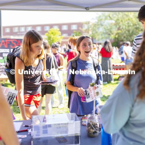 Morgan Tracy, a freshman from St. Louis, reacts as she finds out the person from Lutheran Student Center is also from St. Louis. Tracy and Baylee Carter, a freshman from Kansas, were collecting small plants for their rooms at the booth. Club Fair at City Campus. More than 130 recognized student organizations (RSOs) to join for social, professional and leadership interests. RSO members and officers will be on hand to provide details about their organization and answer questions from prospective new members. August 25, 2021. Photo by Craig Chandler / University Communication.