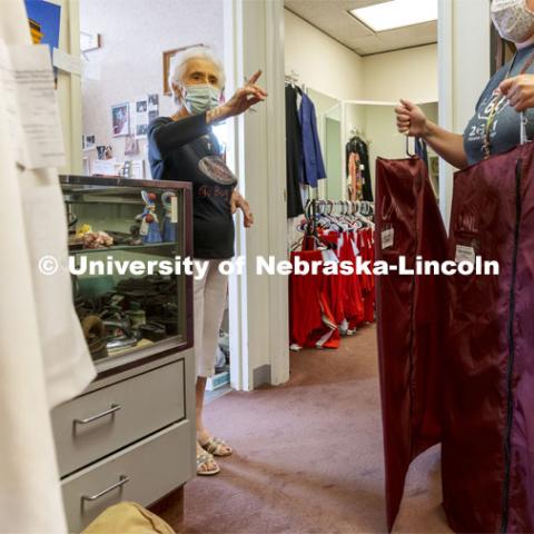 Stamatia Deligiannis directs band members to the correct rack to pick up the finished uniforms. Demetrios and Stamatia Deligiannis have worked together for 51 years in a small shop within the Wells Fargo Building in downtown Lincoln and have been altering the Cornhusker Marching Band uniforms for 50 years from their Lincoln tailoring business. September 1, 2021. Photo by Craig Chandler / University Communication.