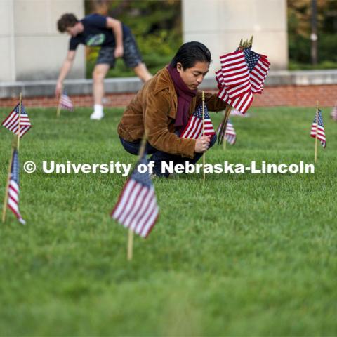 Jerry Saguin, a freshman from San Diego, helps set out flags in the green space north of the Nebraska Union to commemorate 9/11. 9/11 memorials. September 9, 2021. Photo by Craig Chandler / University Communication.