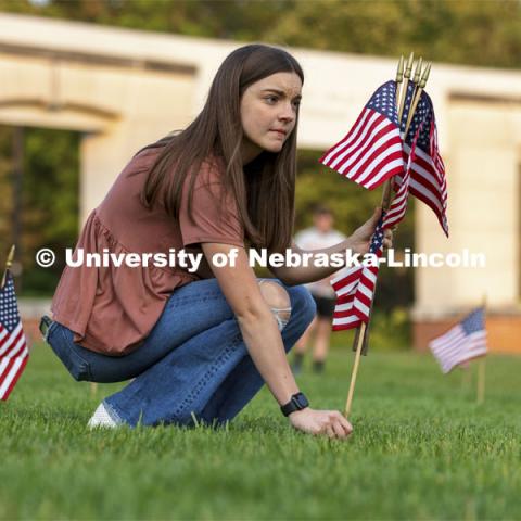 Madi Hadley, a freshman from Gunnison, Colorado, sets up flags in the green space north of the Nebraska Union to commemorate 9/11. Hadley said she has several family members on active duty, and this was a way she could honor their sacrifice. 9/11 memorials. September 9, 2021. Photo by Craig Chandler / University Communication.