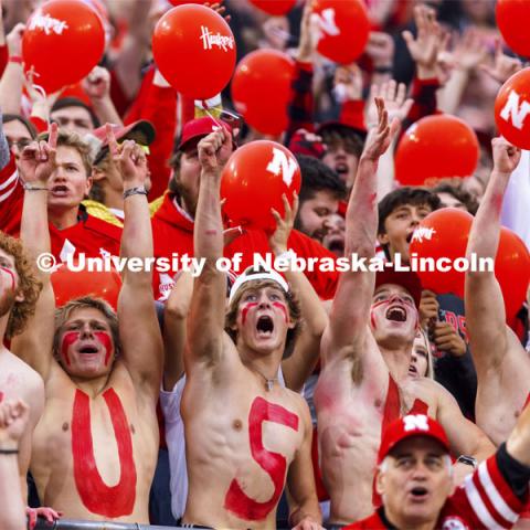 Fans with HUSKERS painted on their chests hold up their cell phone flashlights to light up the stands. Nebraska vs Northwestern University homecoming game. October 2, 2021. Photo by Craig Chandler / University Communication.