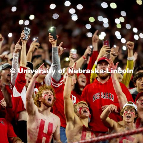 Fans with HUSKERS painted on their chests hold up their cell phone flashlights to light up the stands. Nebraska vs Northwestern University homecoming game. October 2, 2021. Photo by Craig Chandler / University Communication.