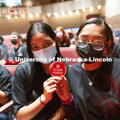 Omaha South seniors Marian Rodriguez and Lizbeth Valente Alday hold up a future Husker sticker from their swag bag. Chancellor Ronnie Green gives admission certificates to Nebraska College Preparatory Academy seniors at Omaha South and Omaha North high schools. November 2, 2021. Photo by Craig Chandler / University Communication.