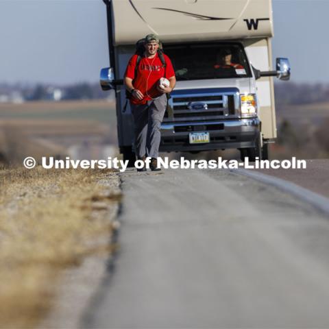 Trevor Stephens, U.S. Marine Corps veteran and a sophomore in secondary education from Council Bluffs, Iowa, walks along Highway 93 westbound from Treynor, Iowa.
Stephens carries the game ball, and 20 pounds in his pack, recognizing the 20 veterans that die from suicide each day. Sixth annual The Things They Carry Ruck March, which began at Kinnick Stadium in Iowa City, Iowa, Nov. 17, and finishes at Memorial Stadium on Friday, Nov. 25. The march, which is organized by the University of Nebraska–Lincoln Student Veterans and University of Iowa Veterans Association organizations, is centered on raising awareness of the epidemic of veteran suicide. It also carries the game ball for the Husker-Hawkeye match-up. November 23, 2021. Photo by Craig Chandler / University Communication.

