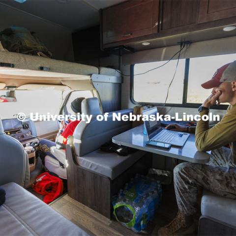 Tyler Kluthe, Marine Corps reservist and a junior construction management major from Lincoln, catches up on homework as he rests in the RV along with Everett Bloom and Dave Rangeloff. The donated RV trails the marcher along the route. Sixth annual The Things They Carry Ruck March, which began at Kinnick Stadium in Iowa City, Iowa, Nov. 17, and finishes at Memorial Stadium on Friday, Nov. 25. The march, which is organized by the University of Nebraska–Lincoln Student Veterans and University of Iowa Veterans Association organizations, is centered on raising awareness of the epidemic of veteran suicide. It also carries the game ball for the Husker-Hawkeye match-up. November 23, 2021. Photo by Craig Chandler / University Communication.