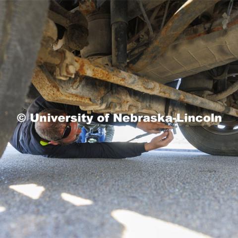 Alex Russell connects the tow cable to a hook under the tractor. Researchers from the Midwest Roadside Safety Facility conducted a rare tractor-tanker crash to test how a newly designed and significantly less tall concrete roadside barrier performs in a crash. The test was at the facility’s Outdoor Proving Grounds on the western edge of the Lincoln Municipal Airport. December 8, 2021. Photo by Craig Chandler / University Communication.