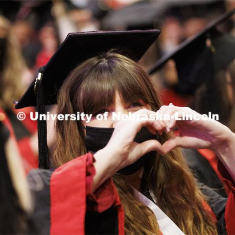 Kellie Roth sends love to her family during the ceremony by making a heart shape with her hands. Undergraduate Commencement at Pinnacle Bank Arena. December 18, 2021. Photo by Craig Chandler / University Communication.