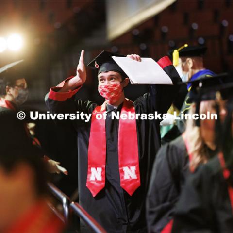 Chase Stubbs gestures to family and friends after receiving his CoJMC diploma. Undergraduate Commencement at Pinnacle Bank Arena. December 18, 2021. Photo by Craig Chandler / University Communication.