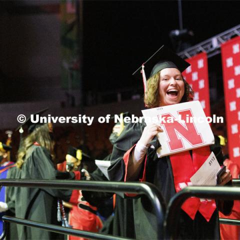 A new grad holds up her diploma and smiles for the camera at the Undergraduate Commencement at Pinnacle Bank Arena. December 18, 2021 Photo by Craig Chandler / University Communication.