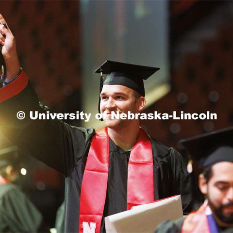 Joshua Wendland points to his friends and family after receiving his computer science diploma on stage. Undergraduate Commencement at Pinnacle Bank Arena. December 18, 2021. Photo by Craig Chandler / University Communication.