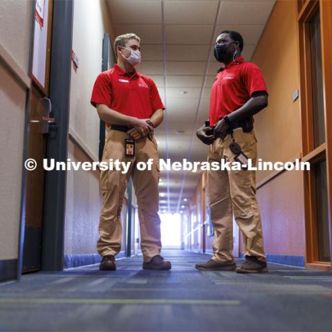 UNLPD Community Service Officers Trevor Caldwell and Komlan Akakpo talk in University Suites hallway. The CSOs are wearing more casual uniforms in 2022. January 7, 2022. Photo by Craig Chandler / University Communication.
