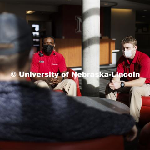 UNLPD Community Service Officers Komlan Akakpo and Trevor Caldwell talk with Cohan Bonow, student and front desk supervisor at University Suites. The CSOs are wearing more casual uniforms in 2022. January 7, 2022. Photo by Craig Chandler / University Communication.