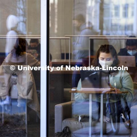 Students walking by are reflected as others study in Love Library. First day of classes for the spring semester. January 18, 2022. Photo by Craig Chandler / University Communication.