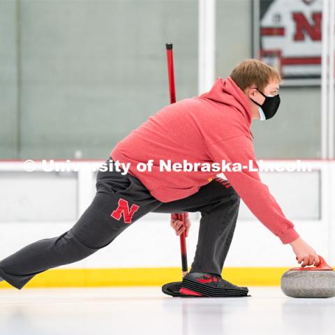 Luke Schroeder serves during curling practice at the John Breslow Ice Hockey Center. Curling Club. February 1, 2022. Photo by Jordan Opp for University Communication.