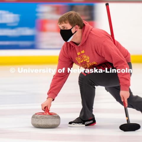 Luke Schroeder serves during curling practice at the John Breslow Ice Hockey Center. Curling Club. February 1, 2022. Photo by Jordan Opp for University Communication.