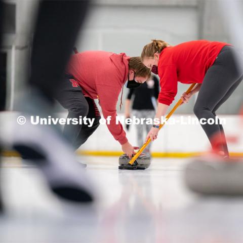 Luke Schroeder (left) Olivia Schuster (right) sweeps during curling practice at the John Breslow Ice Hockey Center. Curling Club. February 1, 2022. Photo by Jordan Opp for University Communication.