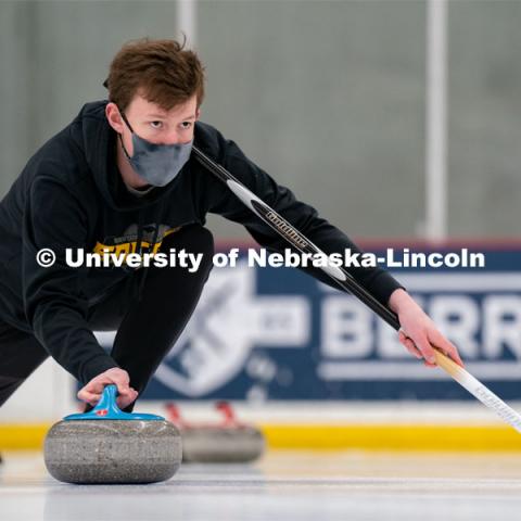Seamus Hurley serves during curling practice at the John Breslow Ice Hockey Center. Curling Club. February 1, 2022. Photo by Jordan Opp for University Communication.