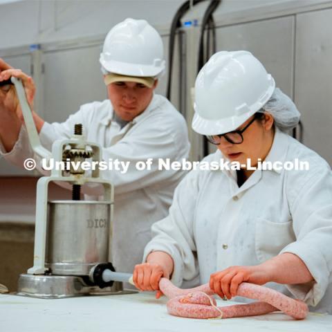 Leila Venzor and Frazier Kaelin demonstrate the sausage-making process. UNL Meat Science club had a Sausage Making 101 course in the Animal Science Complex. February 28, 2022. Photo by Jonah Tran / University Communication.