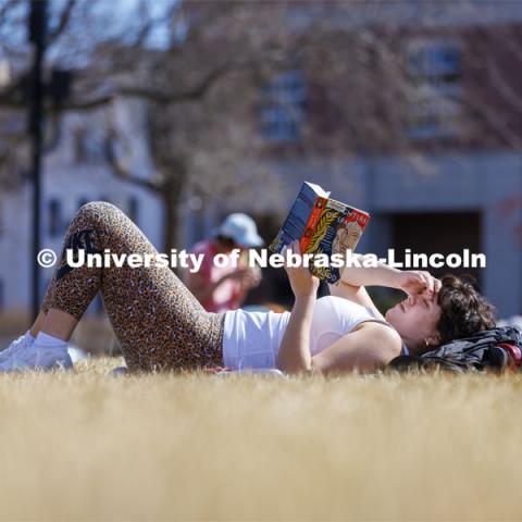 Shelby Serritella, a freshman from Bristol, Wisconsin, catches up on her reading in the greenspace outside the Nebraska Union. Spring on city campus. March 1, 2022. Photo by Craig Chandler / University Communication.