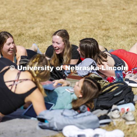 A group of young women take advantage of the nice weather and lay out and visit on the green space between the Union and the Kauffman Academic Residential Center. Spring on city campus. March 1, 2022. Photo by Craig Chandler / University Communication.
