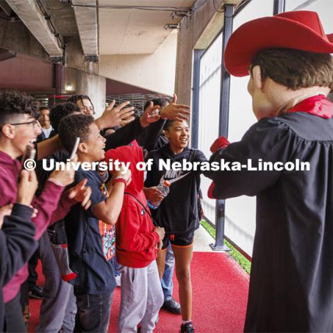 Students from Dawes Middle School in Lincoln meet Herbie Husker during a tour of Memorial Stadium Wednesday given by Dr. Lawrence Chatters, Executive Associate AD for Diversity, Equity and Inclusion. Herbie took time out from a commencement promotional photo shoot to greet his fans. Herbie Husker in cap and gown to promote 2022 spring commencement in Memorial Stadium. May 4, 2022. Photo by Craig Chandler / University Communication.