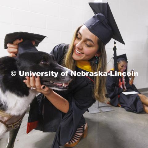 Vilma Maria Montenegro Castro adjusts the mortar board on her service dog, Matty, before the ceremony. Graduate commencement in Pinnacle Bank Arena. May 13, 2022. Photo by Craig Chandler / University Communication.