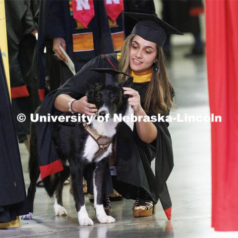 Vilma Maria Montenegro Castro adjusts the mortar board on her service dog, Matty, before the ceremony. Graduate commencement in Pinnacle Bank Arena. May 13, 2022. Photo by Craig Chandler / University Communication.