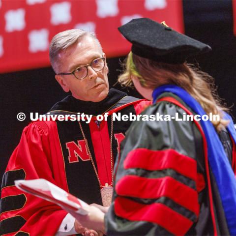 Chancellor Ronnie Green talks with a doctoral degree graduate. He says he enjoys asking each doctoral candidate about their future plans as he hands them their diplomas. Graduate commencement in Pinnacle Bank Arena. May 13, 2022. Photo by Craig Chandler / University Communication.