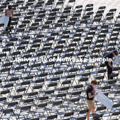 Chairs for Saturday’s undergraduate commencement in Memorial Stadium have been set up and seat numbers are being placed by volunteers. Mats cover the new turf on the field to protect it. May 13, 2022. Photo by Craig Chandler / University Communication.