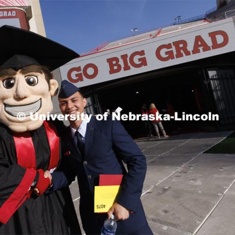 An ROTC student poses with Herbie Husker at the UNL undergraduate commencement in Memorial Stadium. May 14, 2022. Photo by Craig Chandler / University Communication.