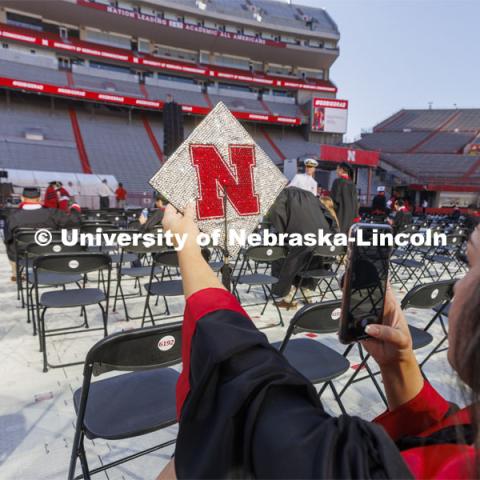 Grace Mann takes a photo of her mortar board before commencement. UNL undergraduate commencement in Memorial Stadium. May 14, 2022. Photo by Craig Chandler / University Communication.