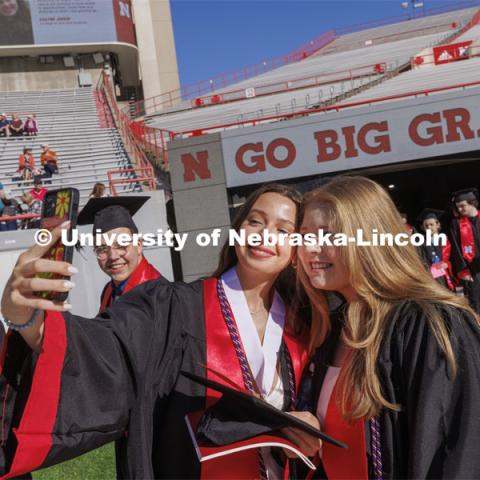 Kelly Shepsko and Matea Spyhalski take a selfie as they enter Memorial Stadium. UNL undergraduate commencement in Memorial Stadium. May 14, 2022. Photo by Craig Chandler / University Communication.