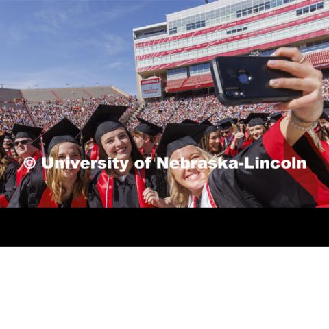 Madalyne Lorenze takes a selfie with her COJMC friends. UNL undergraduate commencement in Memorial Stadium. May 14, 2022. Photo by Craig Chandler / University Communication.