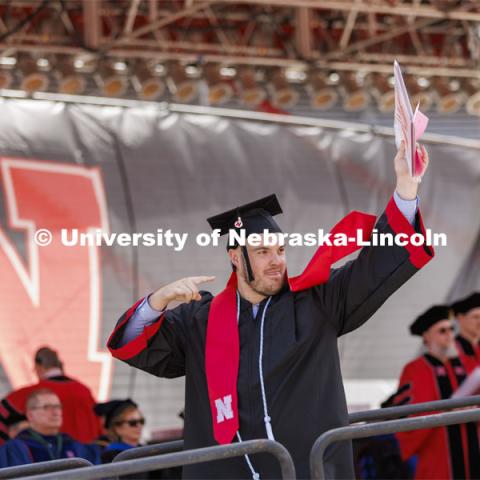 CoJMC graduate Allan Fisher shows off his diploma to family and friends. UNL undergraduate commencement in Memorial Stadium. May 14, 2022. Photo by Craig Chandler / University Communication.