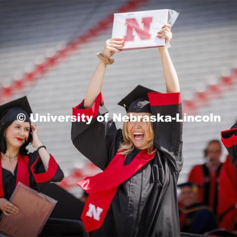 Alayna Verduyn shows off her UNL diploma to friends and family. UNL undergraduate commencement in Memorial Stadium. May 14, 2022. Photo by Craig Chandler / University Communication.