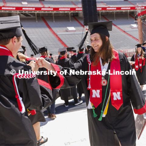 Katelyn Hill high fives a friend after she received her diploma. UNL undergraduate commencement in Memorial Stadium. May 14, 2022. Photo by Craig Chandler / University Communication.