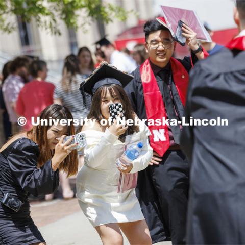 New grads pose for photos with their families. UNL undergraduate commencement in Memorial Stadium. May 14, 2022. Photo by Craig Chandler / University Communication.