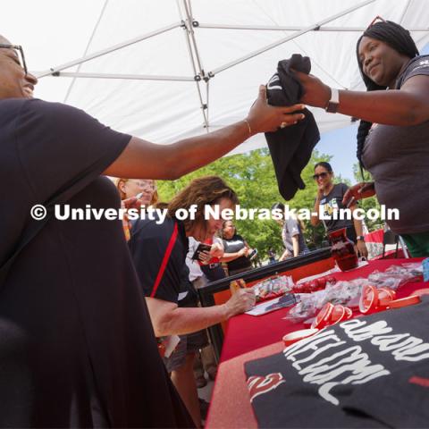 Jerri Harner (right), executive specialist to the vice chancellor for diversity and inclusion, hands out T-shirts from the shade of a canopied table. Juneteenth, the federal holiday that commemorates the emancipation of enslaved Black Americans, is celebrated in an event starting at noon on the Nebraska Union Plaza. June 20, 2022. Photo by Craig Chandler / University Communication.