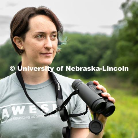 PhD Student Allison Barg looks and listens for different bird species while out checking acoustic monitors at Oak Glen WMA in Seward County. July 6, 2022. Photo by Iris McFarlin, AWESM Lab Communications.