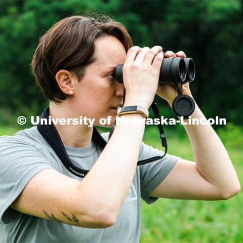 PhD Student Allison Barg looks and listens for different bird species while out checking acoustic monitors at Oak Glen WMA in Seward County. July 6, 2022. Photo by Iris McFarlin, AWESM Lab Communications.