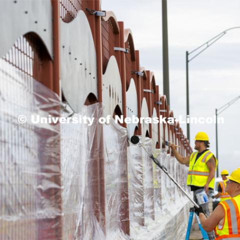 Reni Buehler rolls while Dirk Edwards edges the wave-patterned artwork on the overpass. Building Systems Maintenance paints the artwork on the overpasses of North Antelope Valley Parkway and Salt Creek Roadway. July 7, 2022. Photo by Craig Chandler / University Communication.