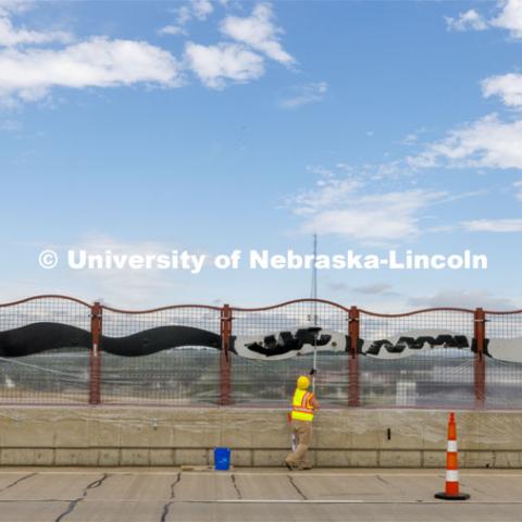 Reni Buehler rolls the wave-patterned artwork on the overpass. Building Systems Maintenance paints the artwork on the overpasses of North Antelope Valley Parkway and Salt Creek Roadway. July 7, 2022. Photo by Craig Chandler / University Communication.