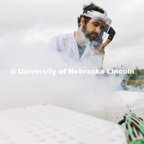 Jon Turkus makes a fog as he combines dry ice from several portable field kits while field phenotyping corn plant DNA in James Schnable’s field northeast of 84th and Havelock. July 8, 2022. Photo by Craig Chandler / University Communication.