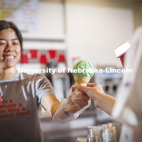 Vi Tran, a senior in actuary science, serves up a cone of Clover 4-H Mint. Ice cream is scooped up at the Dairy Store on East Campus. July 18, 2022. Photo by Craig Chandler / University Communication.