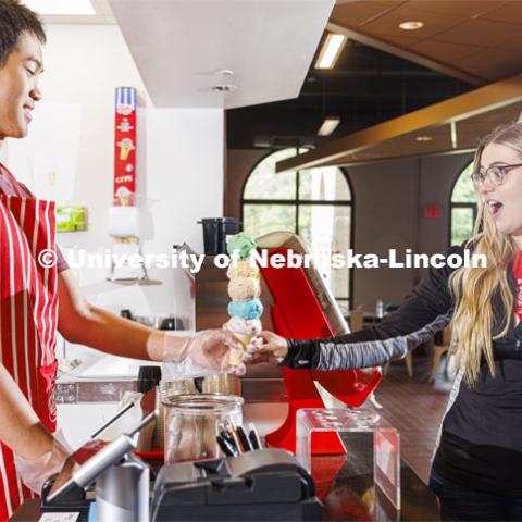 Randy Nguyen (left) serves up a towering five-scoop ice cream cone to Lauren Ahlers, a first-year veterinary medicine student from Rosalie, Nebraska. The handoff and balancing act took place in the middle of National Ice Cream Month at the Dairy Store on East Campus. Ice cream is scooped up at the Dairy Store on East Campus. July 18, 2022. Photo by Craig Chandler / University Communication.