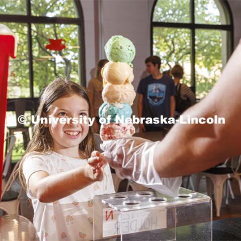 Allie Wiesman, 9, eyes a cone of colorful ice cream. She and her parents are visiting from Kentucky. Ice cream is scooped up at the Dairy Store on East Campus. July 18, 2022. Photo by Craig Chandler / University Communication.