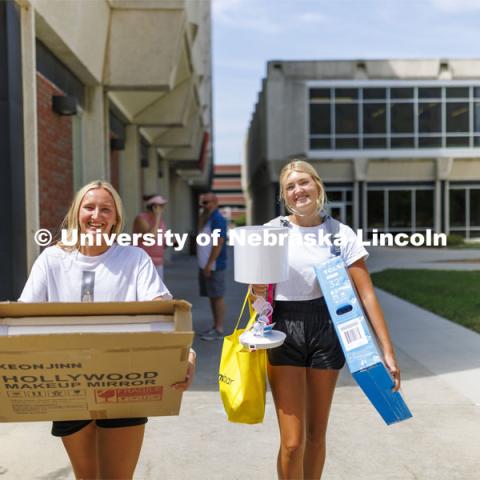 Avery Sindt, right, and her best friend, Skylar Gronewold, carry Sindt’s breakable possessions into Schramm Hall. Residence Hall move in for students participating in Greek Rush. August 14, 2022. Photo by Craig Chandler / University Communication.